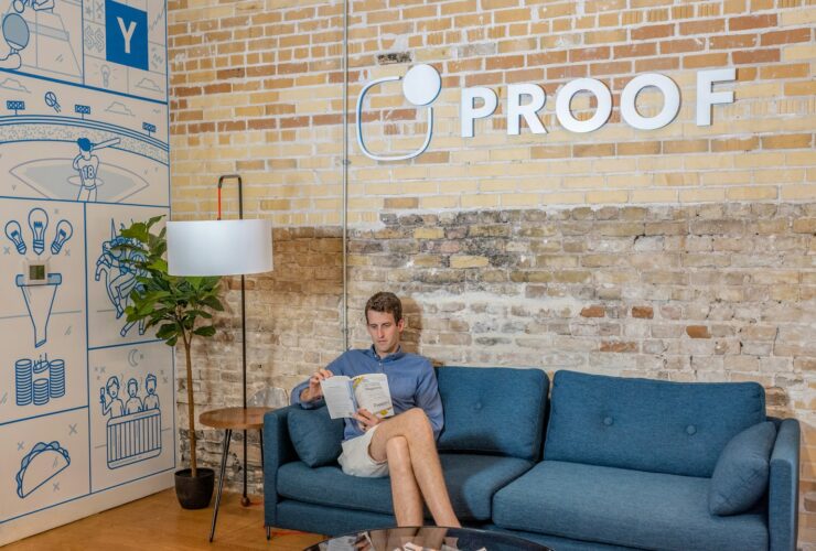 man sitting on blue sofa while reading book