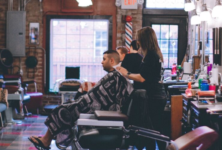 man standing beside man sitting on barber chair